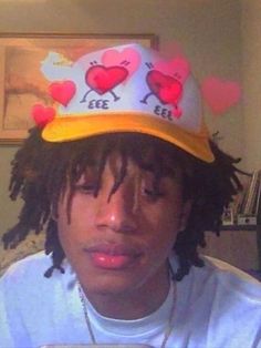 a young man wearing a yellow hat with hearts on it's side and the word love is embellished