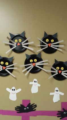 paper plates with black cats, ghost and cat faces on them are hanging from the wall