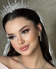 a woman wearing a tiara and makeup looks at the camera while posing for a photo