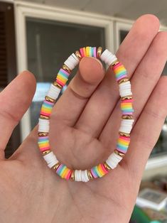 a hand holding a bracelet with multicolored beads