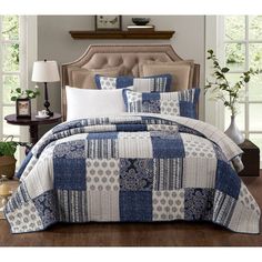 a blue and white quilted comforter set on a bed in a living room