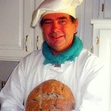 a man in a chef's outfit holding a loaf of bread