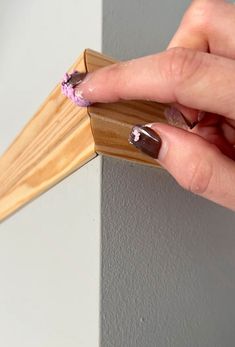 a woman's hand holding a wooden stick with purple flowers on it