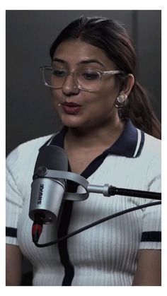 a woman wearing glasses and holding a microphone