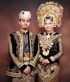 a man and woman dressed in traditional thai garb standing next to each other wearing headdress