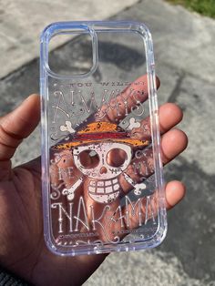 a person holding up a clear case with a skull and pirate's hat on it