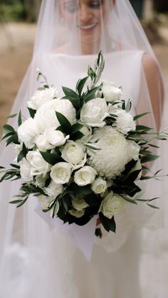 a bride holding a bouquet of white flowers