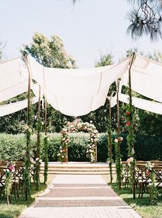 an outdoor ceremony with white draping and flowers