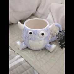 a ceramic mug with eyes and arms on a bed