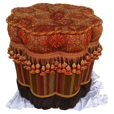 a large brown and red ottoman with tassels