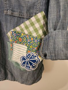 a patched pocket on the back of a jean jacket with flowers and gingham