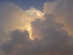 the sky is filled with white clouds as the sun sets in the distance behind it