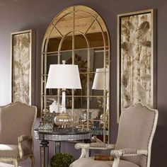 a living room with two chairs and a table in front of a large mirror on the wall