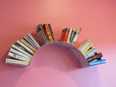 a book shelf with books on it against a pink wall in the shape of an arch