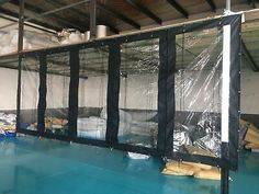 an indoor swimming pool covered in tarp and plastic covering it's walls, with mattresses on the floor