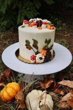 a white cake sitting on top of a table covered in leaves and acorns