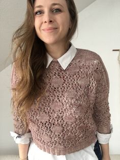 a woman wearing a pink sweater and white shirt