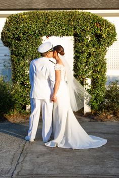 a bride and groom standing in front of a house