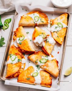 several pieces of pizza on a tray with sour cream and cucumber garnish