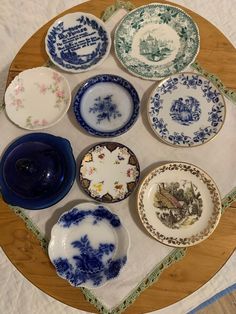 there are many plates on the table with blue and white designs around them, all in different sizes