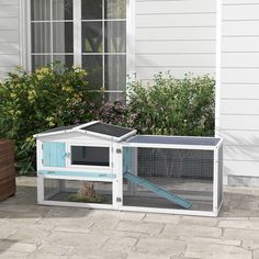 an outdoor rabbit house with a cat in it's cage and flowers behind it