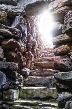 the light shines through an opening in a stone wall with steps leading up to it