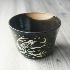 a black and white cup sitting on top of a wooden table