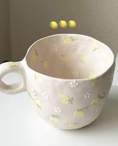 a cup with lemons floating in it on a white table next to a wall