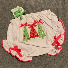 a diaper cover with christmas trees and bows on the bottom is laying next to a pair of scissors