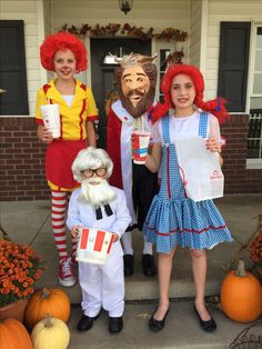 three children in costumes standing on the front porch