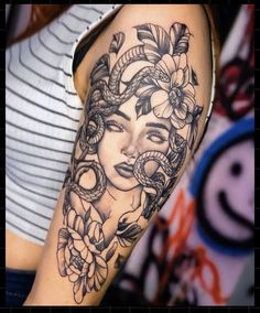 a woman's face with flowers and snakes around her head on the right arm