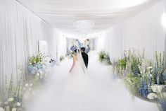 a bride and groom are walking down the aisle in their wedding gowns with flowers on either side