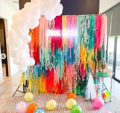 balloons, streamers and streamers are on the floor in front of a colorful backdrop