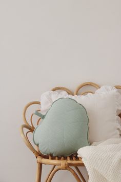 a wicker chair with pillows and blankets on it in front of a white wall