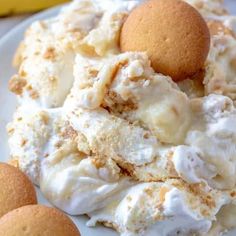 a white plate topped with whipped cream next to two cookies and a banana on the side