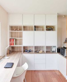 a kitchen with white cabinets and wooden floors, along with a laptop on the counter