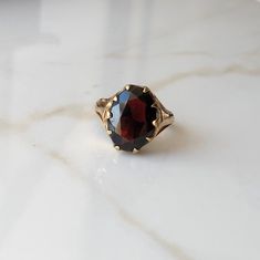 A Vintage 9 carat yellow gold Garnet ring. This beautiful piece holds a large deep red stone in a gold setting. CONDITION: Wear consistent with age and use. Please see photos for more detail. HALLMARKED 9 CARAT GOLD, ASSAYED IN LONDON 1977 STONE SIZE (SETTING): 14mm x 11mm  SETTING HEIGHT: 5mm BAND WIDTH: 2mm RING SIZE: US: 6 | UK: L 1/4 WEIGHT: 3.2 grams (UZZ) Antique Ruby Signet Ring For Formal Occasions, Antique Ruby Rings With Polished Finish, Elegant Faceted Ruby Ring For Formal Occasions, Elegant Formal Faceted Ruby Ring, Classic Yellow Gold Garnet Rings, Vintage Oval Garnet Birthstone Ring, Classic Garnet Signet Ring For Formal Occasions, Classic Garnet Signet Ring For Anniversary, Vintage Garnet Rings With Polished Finish