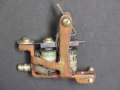 an old style tattoo machine on a gray surface with the needle removed from it's end