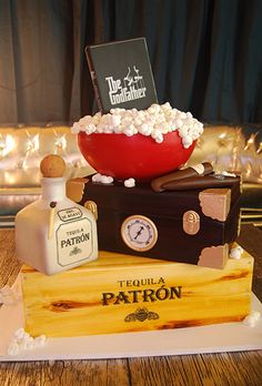 there is a cake made to look like a suitcase with popcorn on top and a bottle of liquor next to it