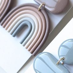 a pair of pastel blue and pink earrings with gold ear wires on top of a white box