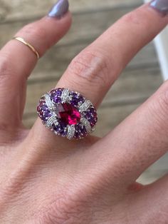 The center stone in this ring is just stunning with deep pink saturation of the stone. . The center piece is a genuine pink tourmaline measuring 7.75mm x 5.75mm, and it has a beautiful checkerboard cut for additional sparkle. The pink tourmaline is accompanied by genuine deep purple amethyst, pale rose amethysts, and additional pink tourmaline round stones.  There are round diamonds totaling approximately .16ctw G/SI1 This ring is super comfortable.  It slides so nicely on the finger and feels v Luxury Pink Gemstone With Center Stone, Luxury Multi-stone Pink Gemstones, Luxury Pink Multi-stone Gemstones, Oval Multi-stone Ruby Ring, Luxury Oval Ruby Ring With Gemstone, Exquisite Oval Ruby Ring With Center Stone, Luxury Pink Sapphire Ring With Gemstone Accents, Formal Pink Amethyst Ring With Gemstone Accents, Luxury Pink Amethyst Gemstone Ring