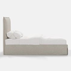 an upholstered bed with white linens and pillows on the headboard is shown