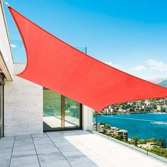 an outdoor area with a large red shade on the roof and water in the background