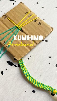 an origami kite made out of brown paper with green and yellow string attached to it