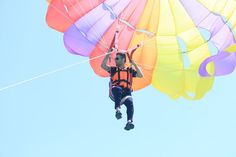 a man is parasailing in the air with colorful parachutes on his back