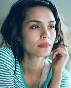 a young woman sitting down with her hand on her chin and looking off to the side