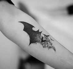 a black and white photo of a bat tattoo on the arm