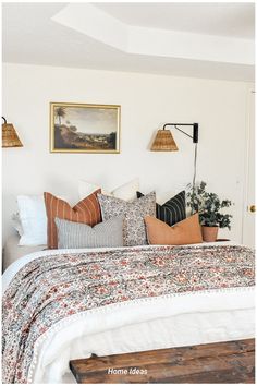 a bed with lots of pillows on top of it and pictures above the headboard