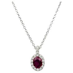 Elevate your elegance with this exquisite oval cut natural ruby and diamond halo pendant necklace in 18 karat white gold. This stunning piece features a vibrant oval cut ruby, renowned for its rich, captivating red hue. Surrounding the ruby is a delicate halo of sparkling diamonds, enhancing the gemstone's brilliance and adding a touch of timeless glamour. The pendant is gracefully suspended from a delicate 18 inch cable chain, crafted from luxurious 18 karat white gold. The chain's subtle elegance perfectly complements the pendant, allowing the radiant ruby and diamonds to take center stage. This necklace effortlessly combines sophistication and style, making it an ideal accessory for any occasion. Whether worn for a special event or to add a touch of luxury to everyday attire, this neckl Ruby Necklace Pendant, Timeless Glamour, Gold Snake Chain, Sparkle Necklace, Ruby Pendant, Halo Pendant, Red Diamond, Classy Jewelry, Modern Necklaces