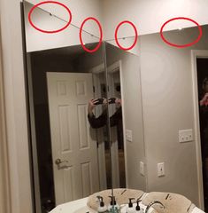 a man taking a selfie in front of a mirror with red circles on it